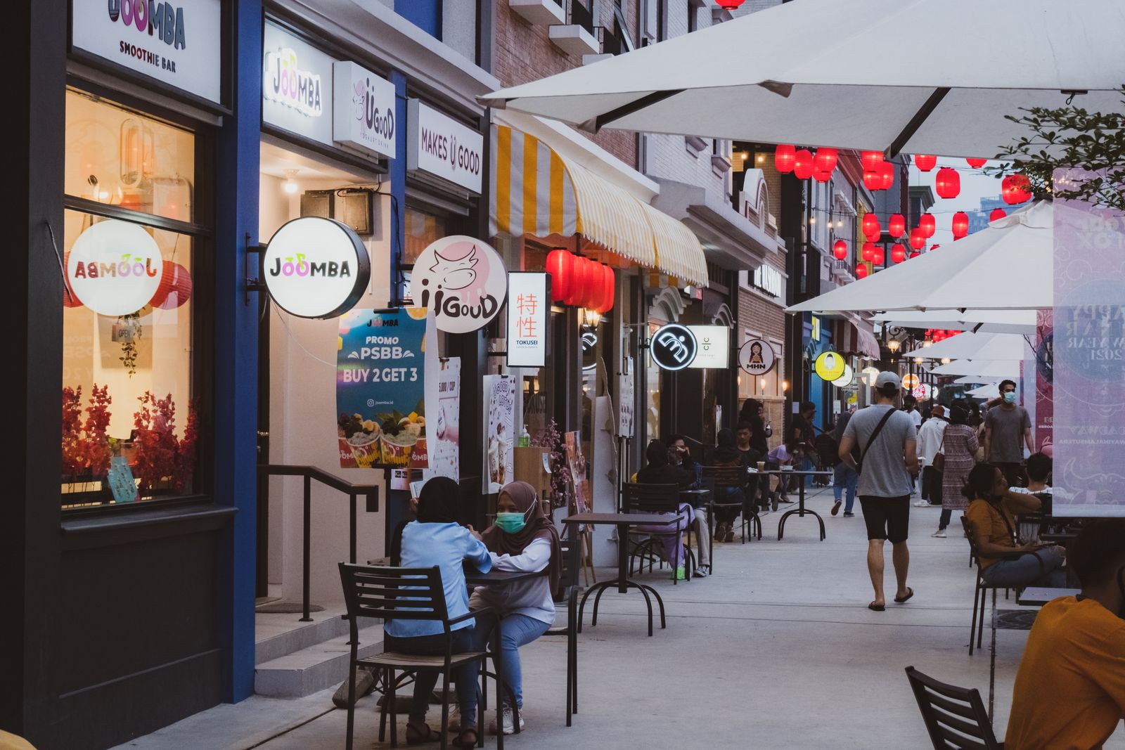 An evening shopping street with lit storefronts